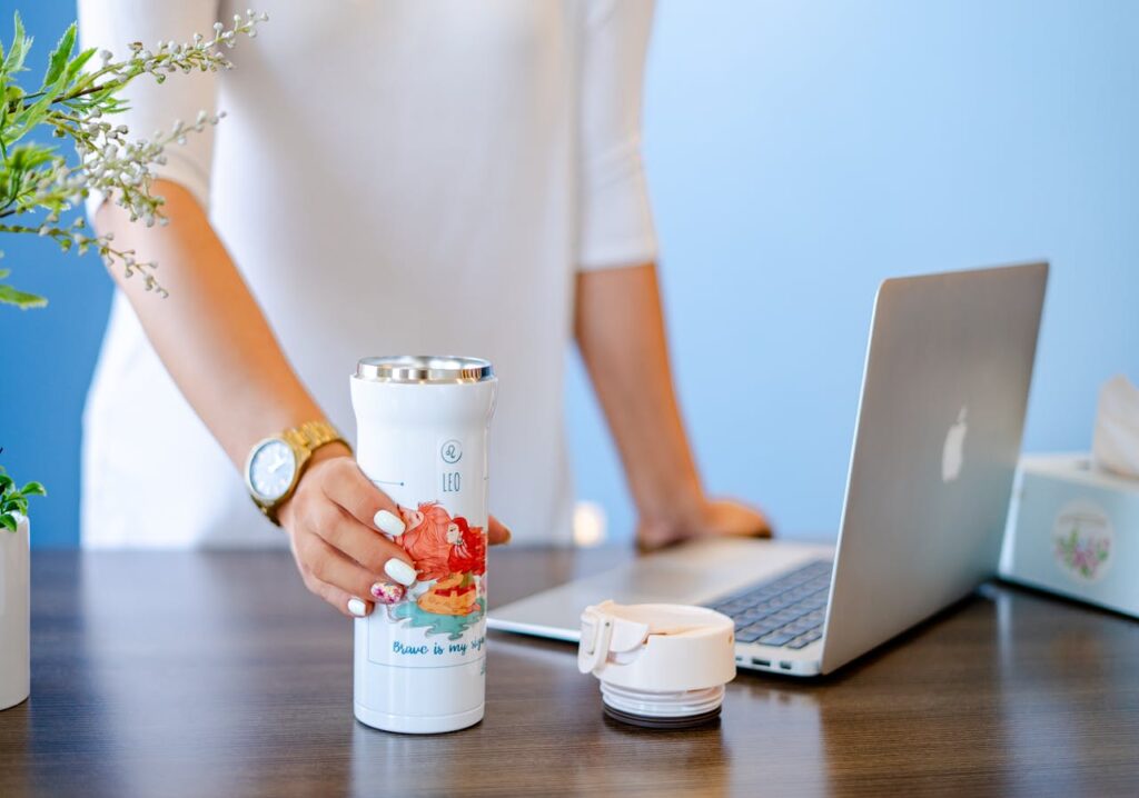 Shallow Focus Photo of Macbook Beside White Tumbler